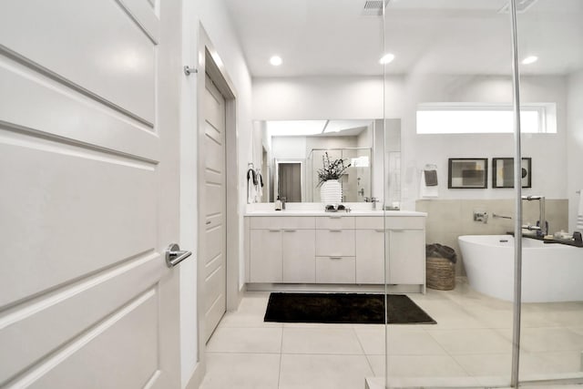 bathroom with tile patterned flooring, vanity, a tub, and tile walls