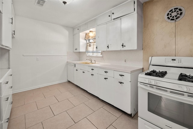 kitchen with light tile patterned flooring, sink, white gas range oven, and white cabinets