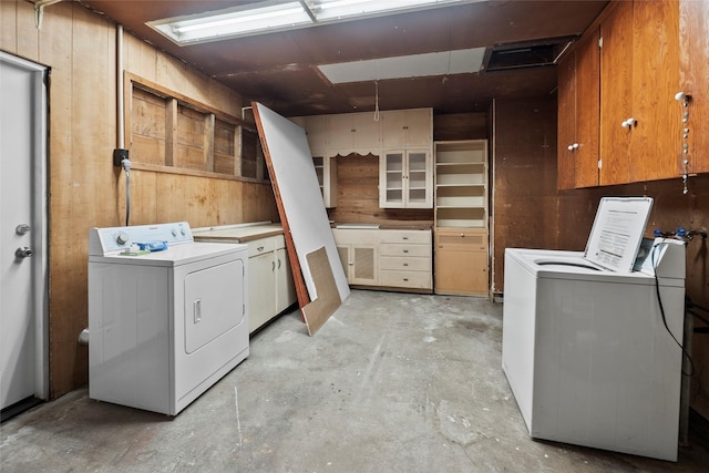 laundry room featuring cabinets, separate washer and dryer, and wood walls