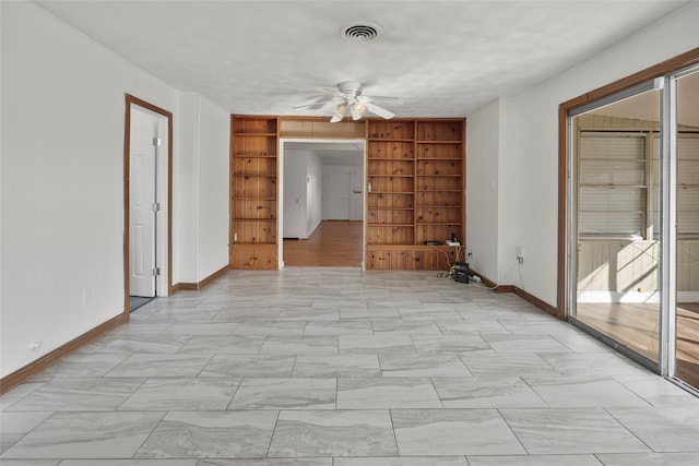 empty room with built in shelves and ceiling fan