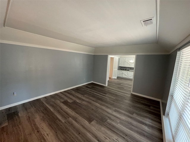 spare room with dark wood-type flooring, crown molding, and vaulted ceiling