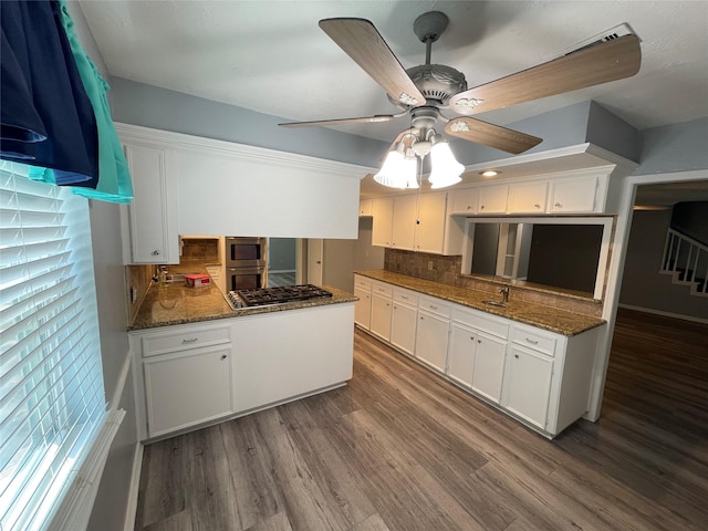 kitchen featuring dark wood-type flooring, kitchen peninsula, stainless steel appliances, decorative backsplash, and white cabinets