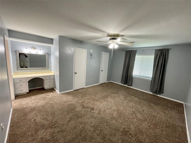 unfurnished bedroom featuring multiple closets, built in desk, ceiling fan, and carpet