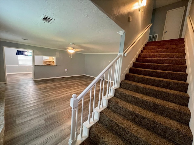 staircase with hardwood / wood-style floors, ornamental molding, and a textured ceiling