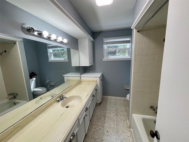 full bathroom with washer / clothes dryer, vanity, tiled shower / bath, and toilet