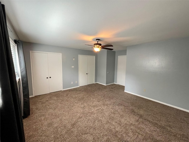 unfurnished bedroom with carpet flooring, two closets, and ceiling fan