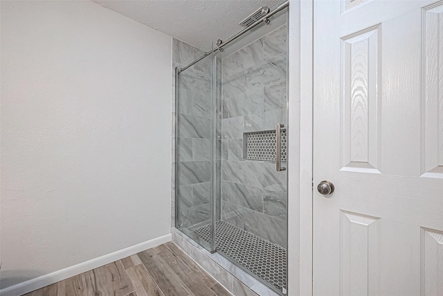 bathroom featuring wood-type flooring, a shower with door, and a textured ceiling