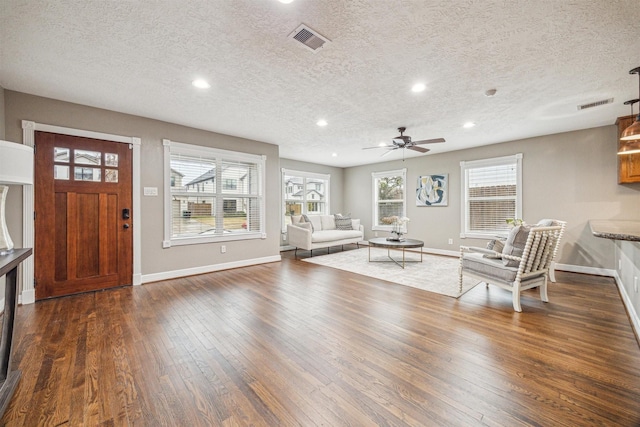 unfurnished living room featuring ceiling fan, dark hardwood / wood-style flooring, and a textured ceiling