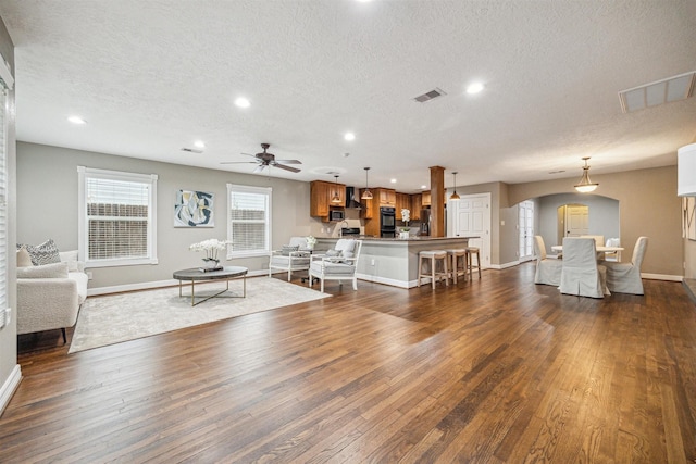 living room featuring ceiling fan, dark hardwood / wood-style flooring, and a textured ceiling