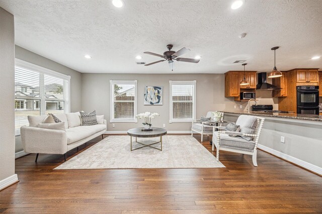 living room featuring dark wood-type flooring, ceiling fan, and a textured ceiling