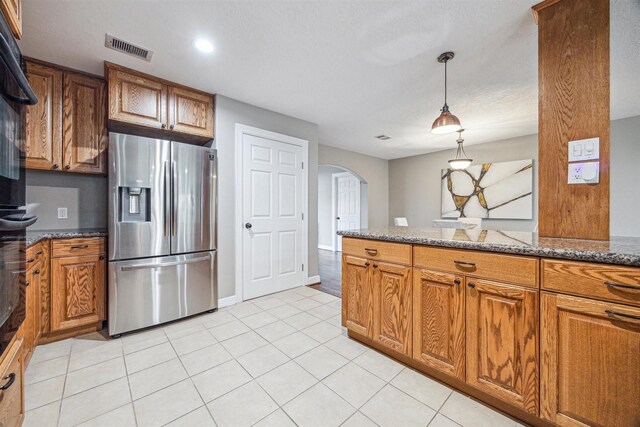 kitchen featuring dark stone counters, stainless steel fridge with ice dispenser, hanging light fixtures, and light tile patterned floors