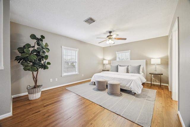 bedroom featuring ceiling fan, wood-type flooring, and a textured ceiling