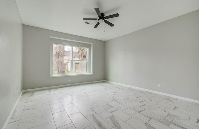 empty room with marble finish floor, baseboards, visible vents, and ceiling fan