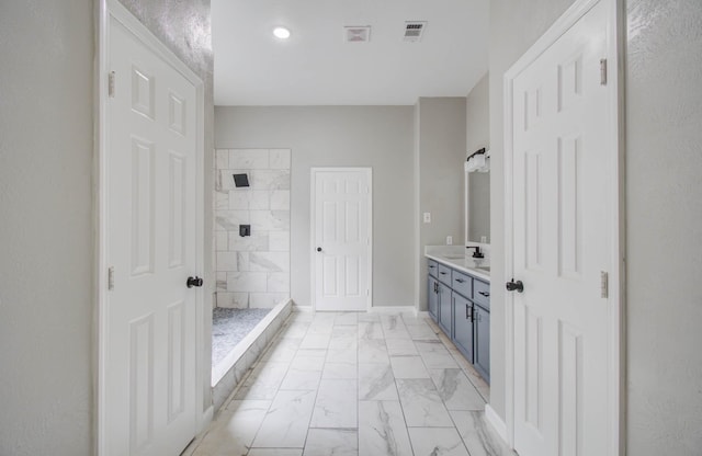 bathroom featuring marble finish floor, visible vents, a tile shower, vanity, and baseboards