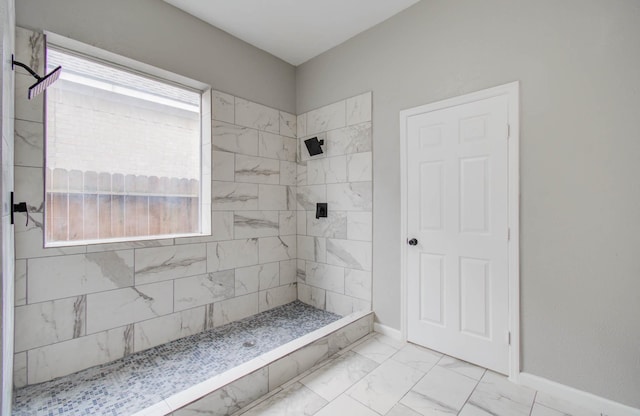 full bathroom featuring marble finish floor, a tile shower, and baseboards