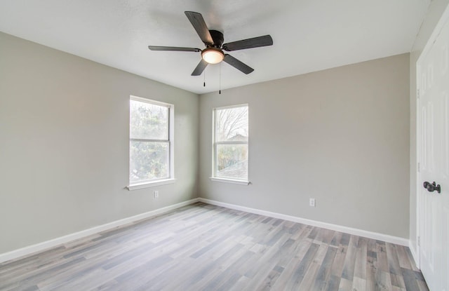 spare room with wood finished floors, a ceiling fan, and baseboards