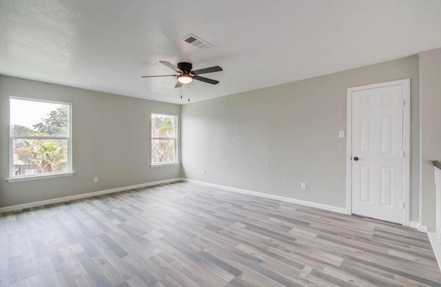 spare room featuring light wood-type flooring, visible vents, baseboards, and ceiling fan