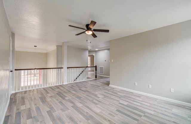 spare room featuring light wood-style floors, visible vents, ceiling fan, and baseboards