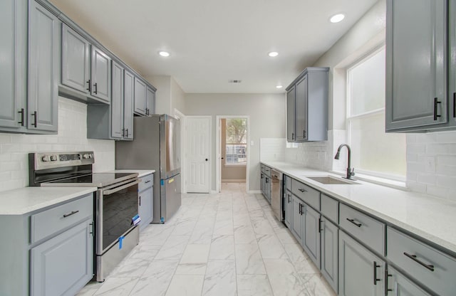 kitchen with visible vents, appliances with stainless steel finishes, marble finish floor, light countertops, and a sink