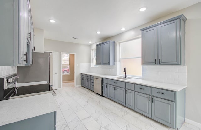 kitchen featuring marble finish floor, tasteful backsplash, light countertops, appliances with stainless steel finishes, and a sink