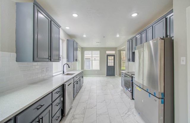 kitchen featuring a sink, marble finish floor, stainless steel appliances, backsplash, and recessed lighting