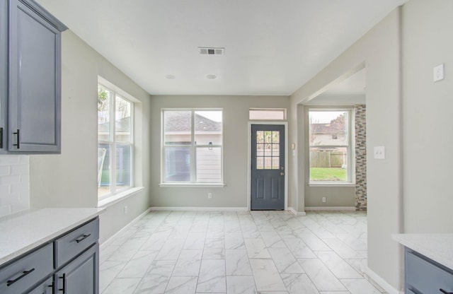 interior space featuring a healthy amount of sunlight, marble finish floor, baseboards, and visible vents