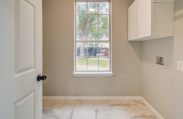 clothes washing area with cabinet space, hookup for a washing machine, marble finish floor, and a wealth of natural light