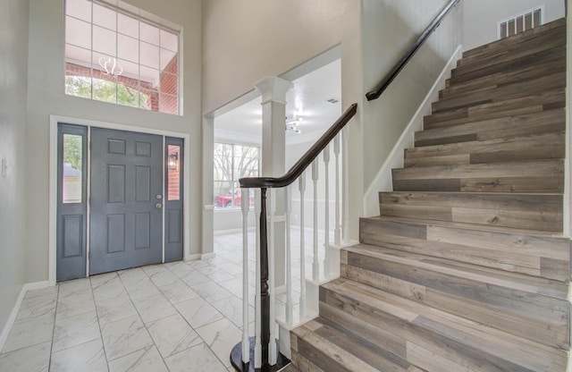 foyer with visible vents, baseboards, marble finish floor, stairs, and ornate columns