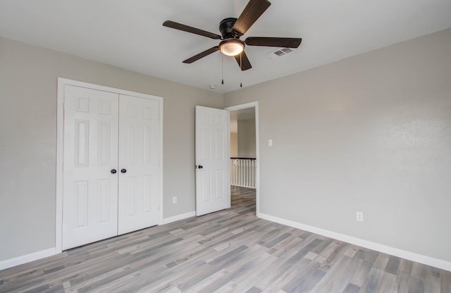 unfurnished bedroom featuring light wood finished floors, visible vents, baseboards, and a closet