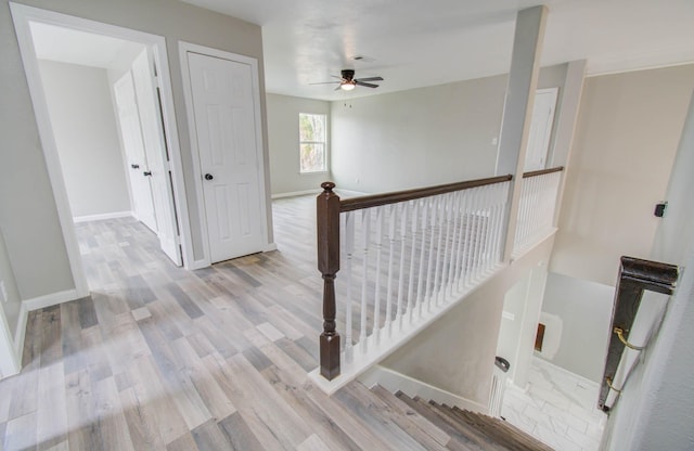 hallway with baseboards, an upstairs landing, and wood finished floors