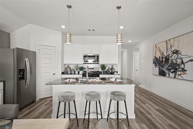 kitchen with stainless steel appliances, hanging light fixtures, a center island with sink, and white cabinets