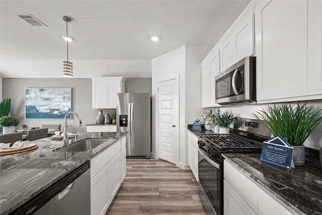 kitchen featuring sink, hanging light fixtures, dark stone countertops, appliances with stainless steel finishes, and white cabinets