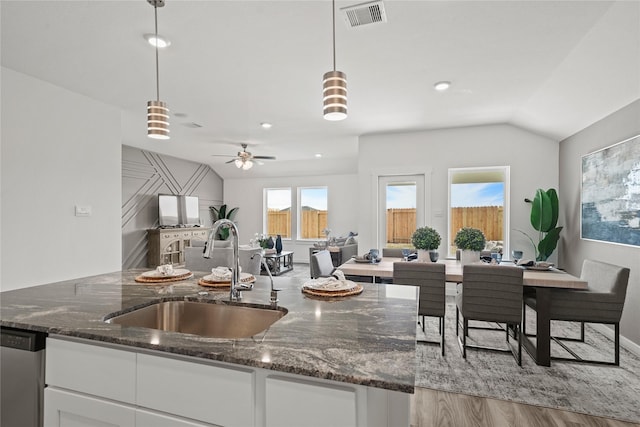 kitchen featuring dark stone countertops, sink, pendant lighting, and white cabinets