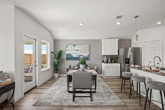 dining room featuring lofted ceiling, sink, and wood-type flooring