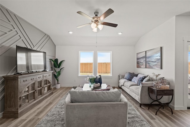 living room with ceiling fan, vaulted ceiling, and light wood-type flooring