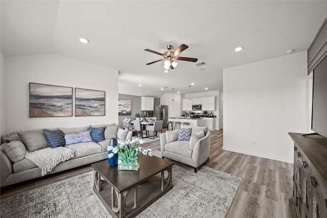 living room with vaulted ceiling, ceiling fan, and light hardwood / wood-style flooring