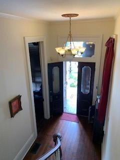 entrance foyer with crown molding, dark hardwood / wood-style floors, and a notable chandelier