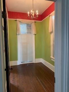 empty room featuring hardwood / wood-style floors and a chandelier