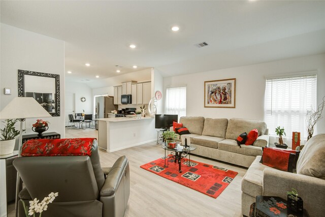 living area featuring recessed lighting, plenty of natural light, visible vents, and light wood-style floors