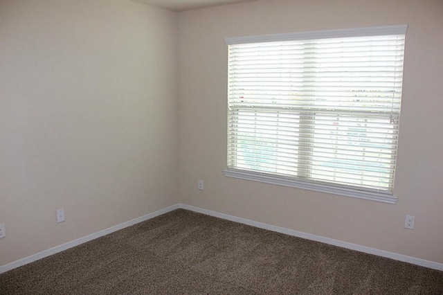 carpeted empty room featuring baseboards