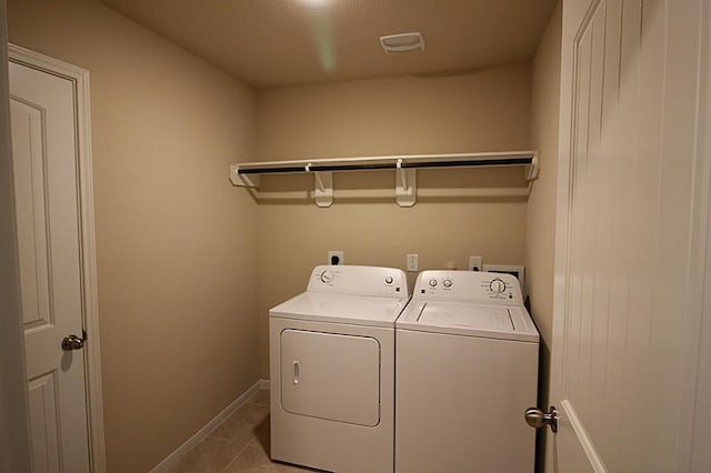 clothes washing area featuring washing machine and clothes dryer, light tile patterned floors, visible vents, laundry area, and baseboards