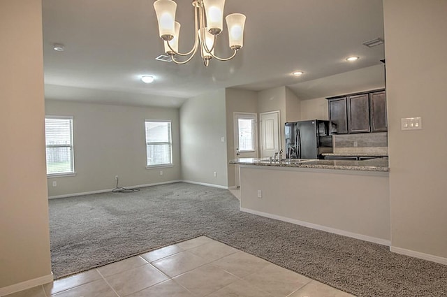 kitchen featuring light colored carpet, visible vents, dark brown cabinets, light stone countertops, and black fridge