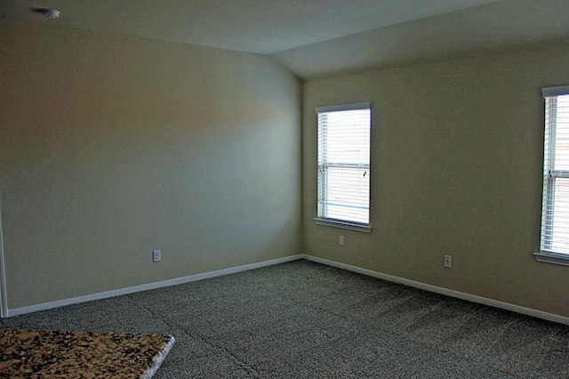 carpeted empty room featuring lofted ceiling and baseboards