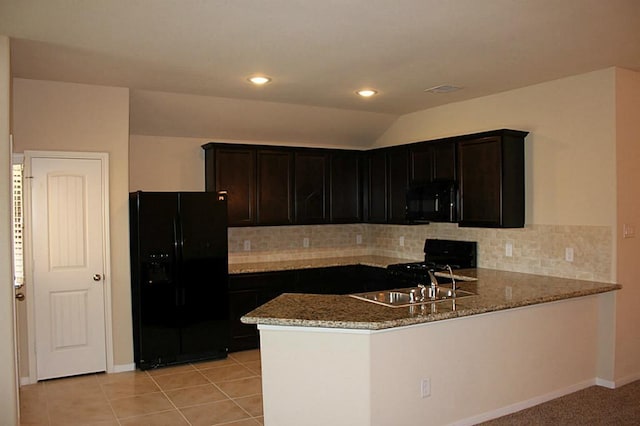 kitchen featuring light tile patterned floors, black appliances, light stone counters, and a peninsula