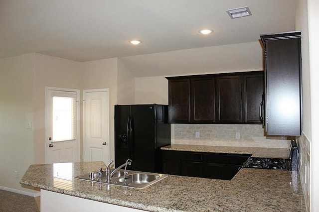 kitchen featuring visible vents, decorative backsplash, freestanding refrigerator, light stone countertops, and a sink