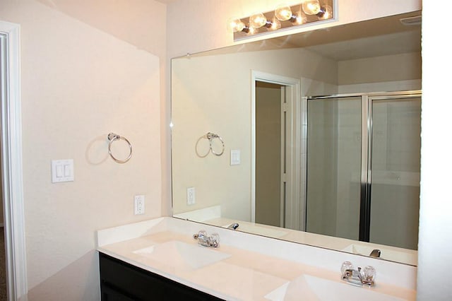 full bathroom with a stall shower, a sink, and double vanity