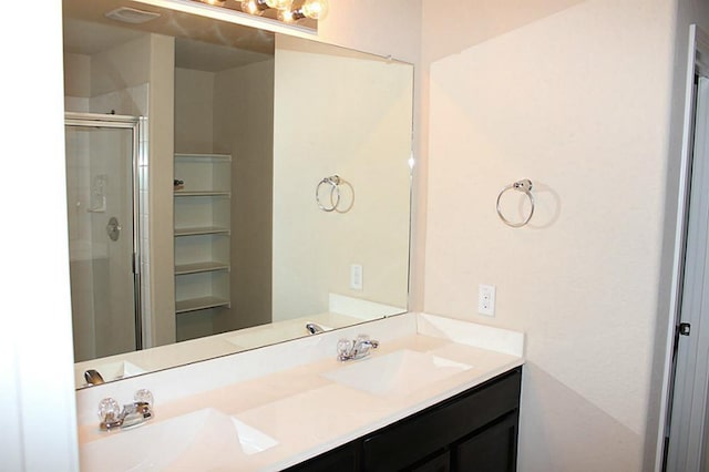 bathroom with double vanity, a shower stall, and a sink