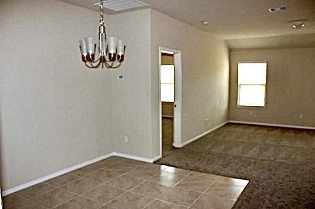 empty room with a chandelier and baseboards