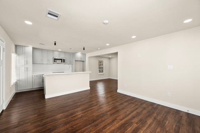 kitchen with dark wood-type flooring, gray cabinets, a center island, and decorative backsplash