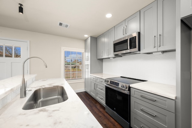 kitchen featuring gray cabinets, light stone countertops, appliances with stainless steel finishes, and sink